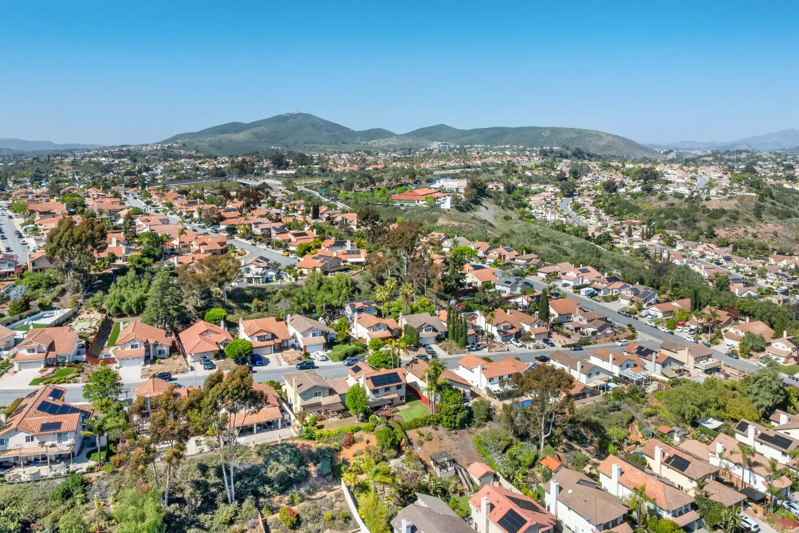 Aerial view of a residential area showcasing homes, greenery, and surrounding hills.