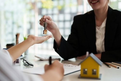 Real estate agent handing over house keys to client in office.