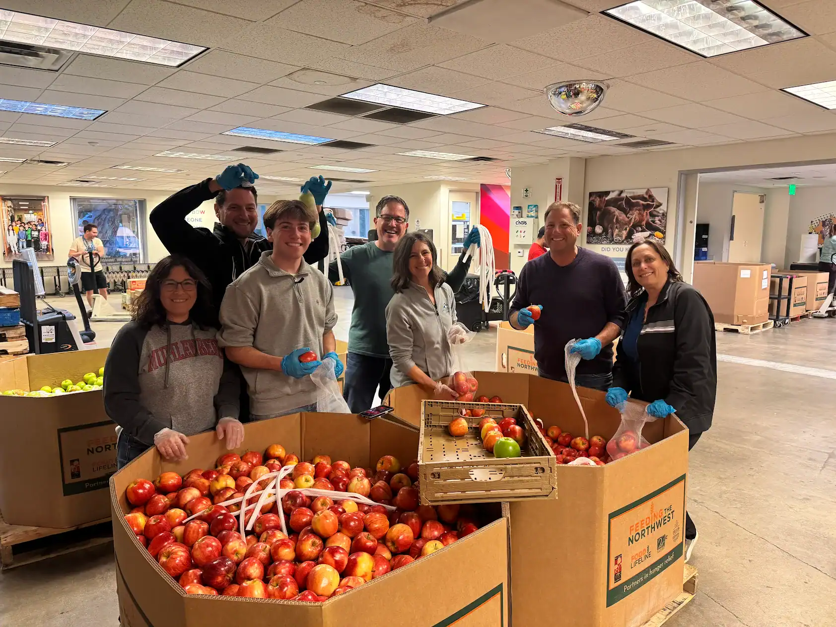Group of volunteers packing apples for charity at Legacy Realty Network.