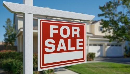 For sale sign in front yard of a residential property.