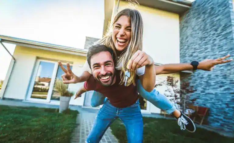 Happy young couple celebrating new home purchase outdoors.